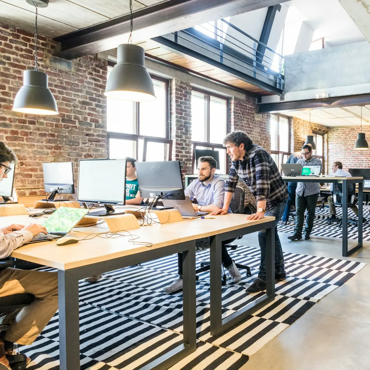 man standing beside another sitting man using computer